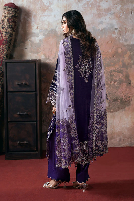 Woman wearing a traditional outfit with a purple and white shawl against a textured wall.